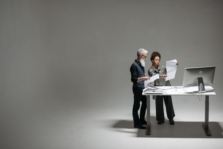 Two professionals analyzing documents and working together at a modern desk.