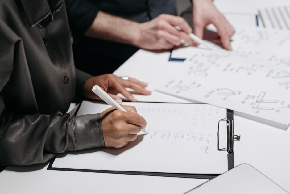 Close-up of team members taking notes and sketching designs during a meeting.