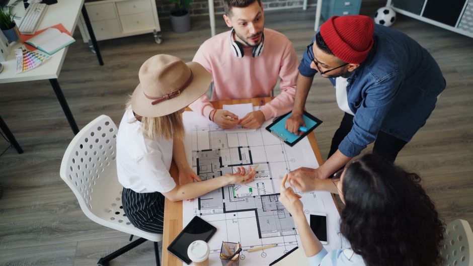 Multiethnic team of designers discussing architectural plans in a modern office.